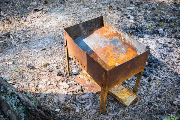Σκουριασμένο σπασμένο Γκριλ μπάρμπεκιου με σκόρπινο κάρβουνο στο έδαφος στο δάσος. — Φωτογραφία Αρχείου