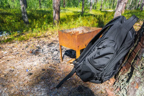 Μαύρο σπορ σακίδιο κόστος για σκουριασμένο μπάρμπεκιου στο δάσος. — Φωτογραφία Αρχείου