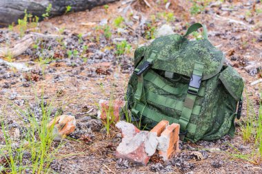 Sırt çantası için sırt çantası yaz ormanda kırmızı renk kırmızı kırık tuğla ile satır, kuru arazi üzerinde yatıyor.