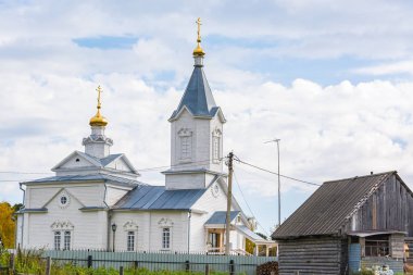Bulutlar ile mavi gökyüzüne karşı kırsal sarı kubbeler ile beyaz ahşap kilise.