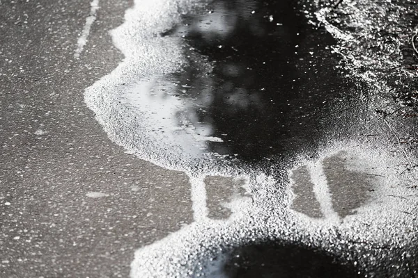 Grande flaque d'eau avec traces humides réparties sur l'asphalte. — Photo