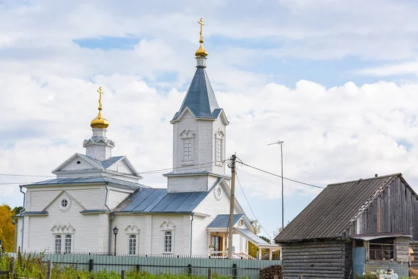 Bulutlar ile mavi gökyüzüne karşı kırsal sarı kubbeler ile beyaz ahşap kilise.