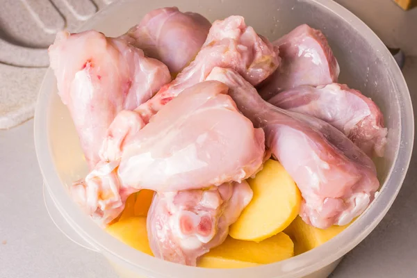 Pernas de frango cru e batatas fatiadas em prato fundo cozido para assar no forno . — Fotografia de Stock