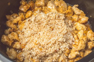 Yavaş ocakpil pilav yapmak için yabani pirinç ve tavuk parçaları döşeme.