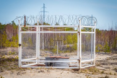 Demir çitli ve dikenli telli bir yağ kompresörü şehrin dışındaki kuma monte edilmişti..