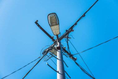 An iron pillar with street lamp and wires through which current flows to the houses.
