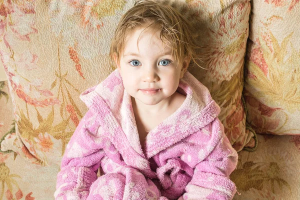Bébé mignon avec cheveux mouillés après le bain dans le peignoir sèche sur le canapé . — Photo