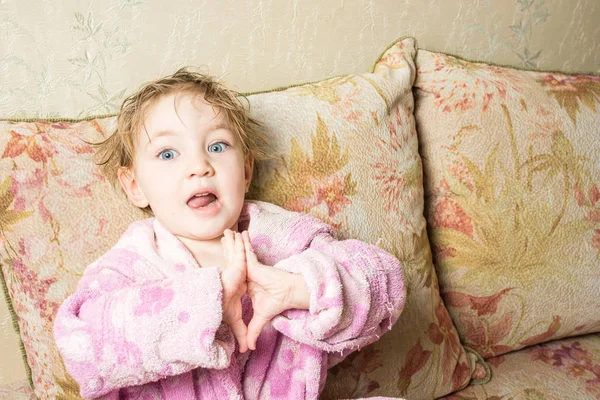 Bebê bonito com cabelo molhado e boca aberta após o banho em roupão mostra os dedos . — Fotografia de Stock