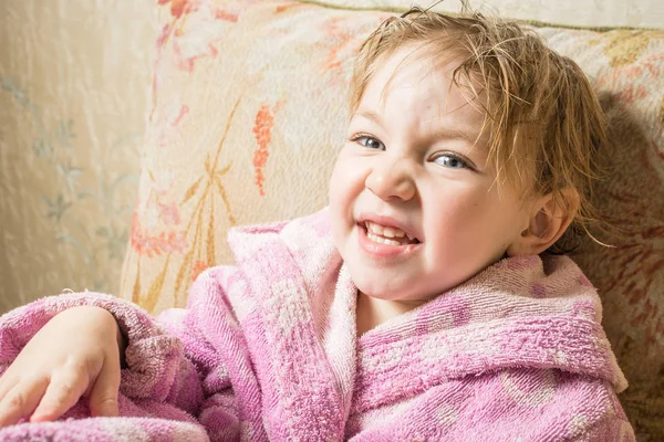 バスローブで入浴後に濡れた髪を持つかわいい赤ちゃんはソファで乾燥します. — ストック写真