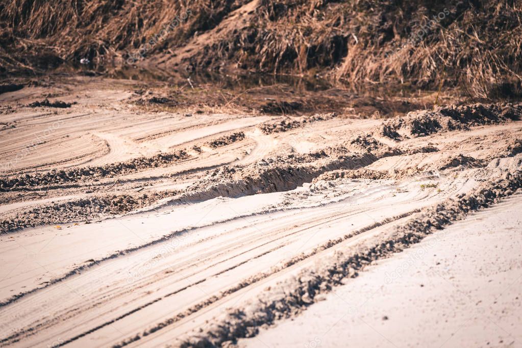 Long tracks from the wheels of passenger car in the sand.