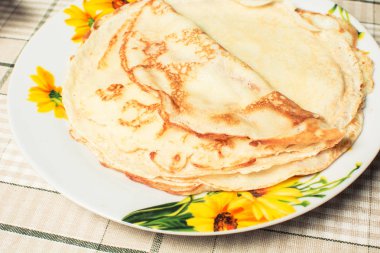 Mutfak masasında tabakta kızarmış yuvarlak krep.