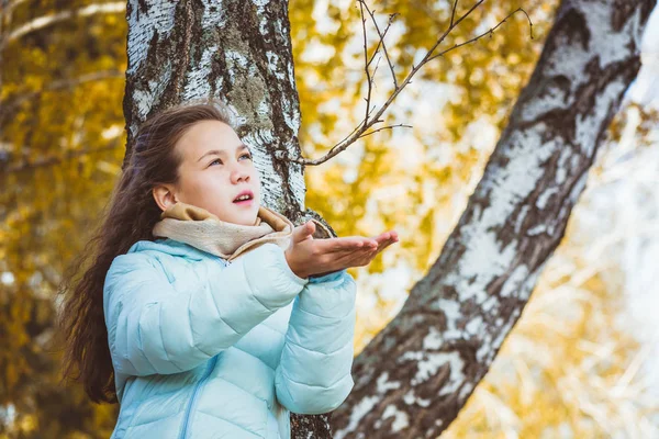 青いダウンジャケットの長い髪を持つ悲しい女の子は、白樺の木に座って、秋の日に雨滴をキャッチ. — ストック写真
