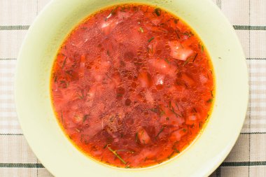 Mutfak masasında yeşil tabakta kırmızı çorba borş.