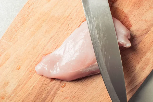 Raw chicken breast fillet with cutting knife on wooden board. — Stock Photo, Image