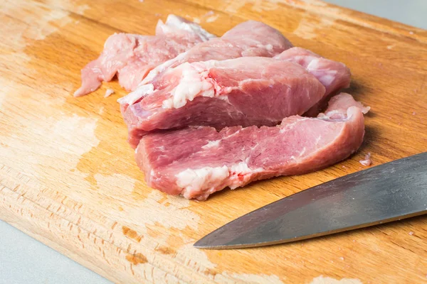 Cut pork meat into pieces with knife on cutting board. — Stock Photo, Image