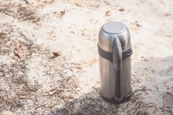 Thermos à thé fermé pour se réchauffer lors d'une randonnée en forêt . — Photo