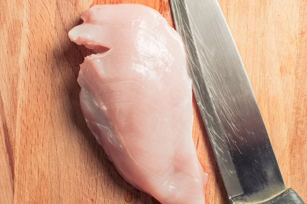 Raw chicken breast fillet with cutting knife on wooden board. — Stock Photo, Image