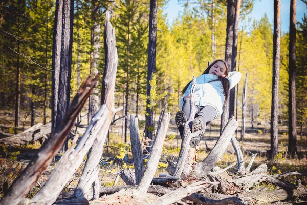 森の中でハイキングした後、倒れた木の上で眠っているライトジャケットとブーツの眠い女の子. — ストック写真