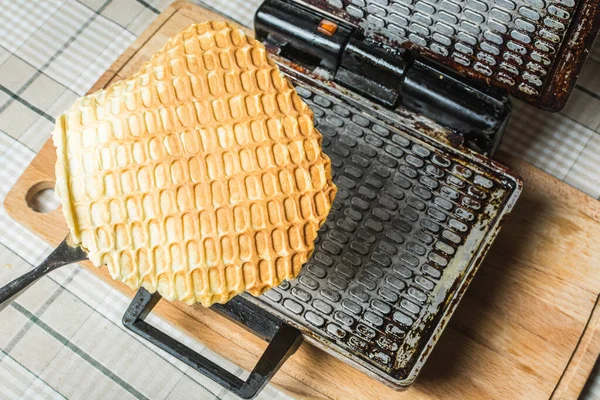 Waffle ızgarasında waffle yaparken mutfak masasını açmak için demir kaşıkla.. — Stok fotoğraf