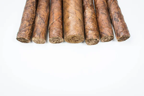 Big and small cigars twisted from sheets of tobacco on white background. — Stock Photo, Image