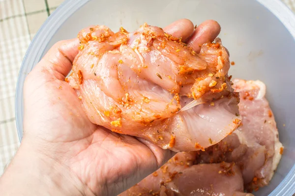 Raw chicken rubbed with spicy spices in male hand over large plate. — Stock Photo, Image
