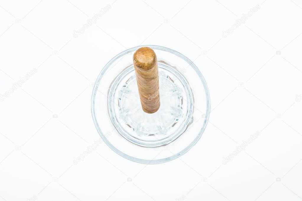 Thick cigar from twisted sheets in glass bowl with white background.