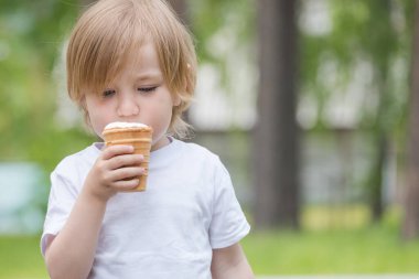Beyaz tişörtlü, mavi gözlü güzel bebek beyaz dondurma yiyor.