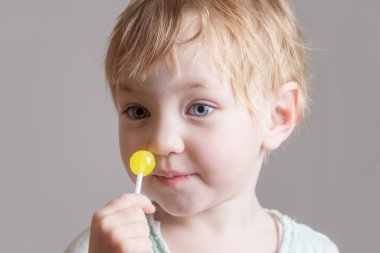 Elinde sarı şeker olan sevimli bir bebek.