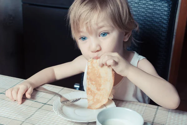 Красивый Ребенок Голубыми Глазами Ест Вкусные Блины Сидя Кухонным Столом — стоковое фото