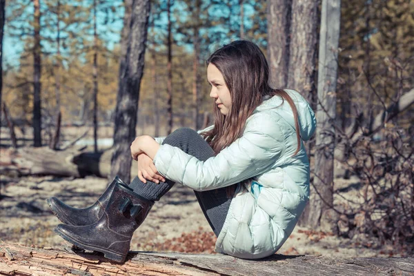 光のジャケットの美しい女の子が座っていると春の森の中で古いスナックに残ります — ストック写真