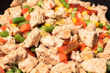 Tavada sebze karışımlı kızarmış tavuk parçaları.