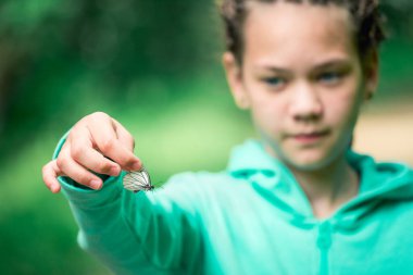 Kafasında rastalı bir kız elinde egzotik bir kelebek tutuyor