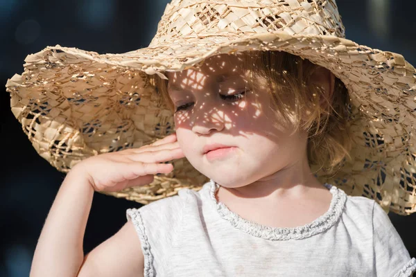 Small child in big hat takes cover from the sun so as not to burn out