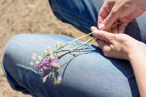 Girl in jeans holds flower branch on her lap