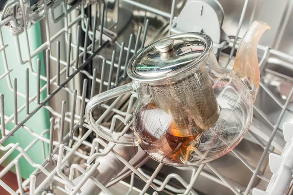 Dirty glass teapot lies in the dishwasher.