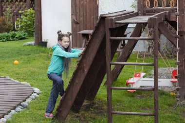 Kafasında rasta olan güzel bir kız oyun bahçesinde oynuyor.