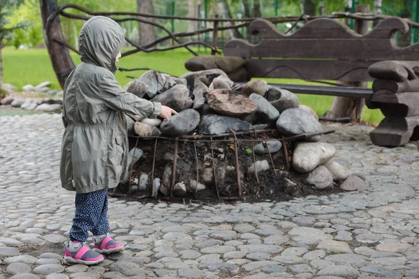 キャンプで絶滅したキャンプファイヤーで開かれたジャケットを着た小さな子供 — ストック写真