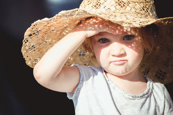 大きな帽子の小さな子供は燃え尽きることのないように太陽からカバーを取ります — ストック写真