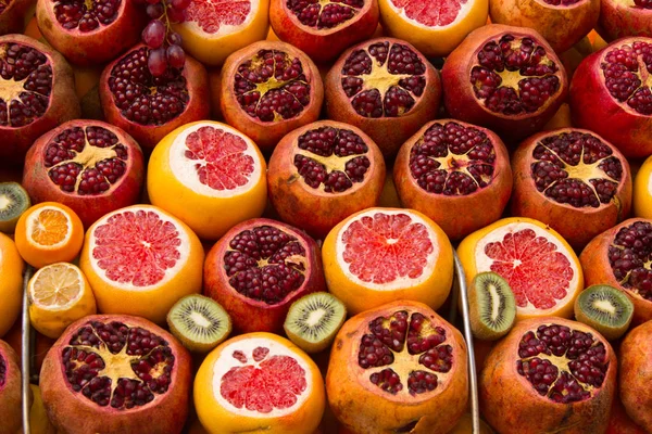 Pazar rafında süslenmiş turuncu, nar ve kivi.