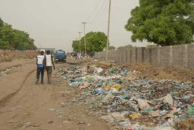 Juba, Güney Sudan, 27 Şubat 2012: Kimliği belirsiz kişi Juba, Güney Sudan bir sokakta çöp döküm tarafından geçiş. Plastik atık geri dönüşüm birçok Afrika ülkeleri için büyük bir sorundur.