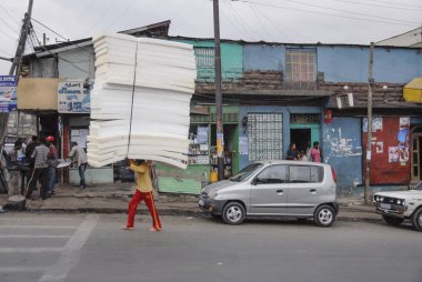ADDIS ABABA, ETHIOPIA, MARCH 30, 2012: Unidentified porter carries pile of foam rubber on his head in Addis Ababa, Ethiopia. Many unemployed local people have to seek random income at market area.