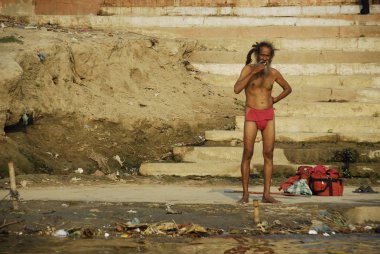 Varanasi, Hindistan, 30 Nisan 2009: Kimliği belirsiz Hint sadhu (kutsal adam) Ganj, Varanasi, Hindistan bir banka üzerinde dişlerini fırçalayıp fırçalamadığını. Birçok Kızılderililer kutsal Ganga'nın su gücüne inanıyoruz.