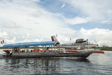 Iquitos, Peru, 29 Nisan 2010: Tekne kimliği belirsiz adam on The Amazon River Iquitos, Peru yakın deniz uçağı tarafından geçer. Nehir ve hava taşıma sadece bu yüzden Iquitos karadan, ulaşılmaz şehir almanın yolu.