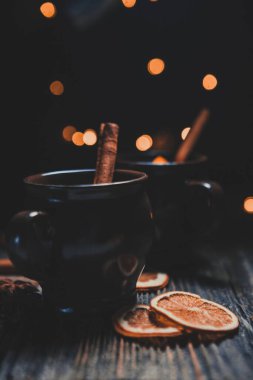 Noel atmosferinde sıcak şarap. Tarçın çubuğu, sıcak şarap. Ahşap bir masada kurumuş portakallar.