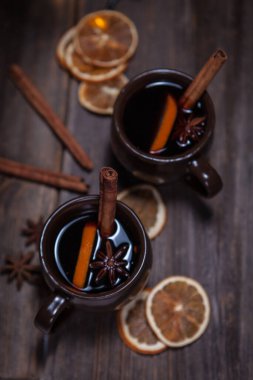 Noel atmosferinde sıcak şarap. Tarçın çubuğu, sıcak şarap. Ahşap bir masada kurumuş portakallar.