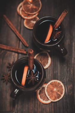 Noel atmosferinde sıcak şarap. Tarçın çubuğu, sıcak şarap. Ahşap bir masada kurumuş portakallar.