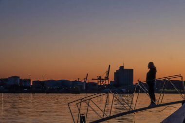 Stockholm, İsveç Bir kadın liman üzerinde gün batımıhayran.