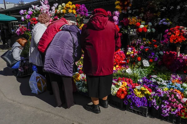 ラトビアリガ市場でイースター用のプラスチック花を選ぶ年配の女性 — ストック写真