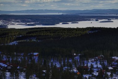Orsa, Dalarna eyaleti, İsveç güneşli bir kış gününde donmuş Orsa Gölü üzerinde görünümler.