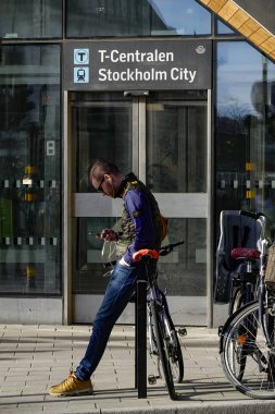 Stockholm, İsveç Genç bir adam şehir merkezinde T-Centralen de bisikletine yaslanır.